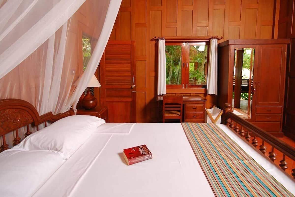 Um quarto de madeira com uma cama, uma escrivaninha e um espelho.