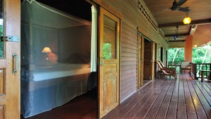 Una habitación de madera con una cama, un ventilador de techo y una mesa con sillas.