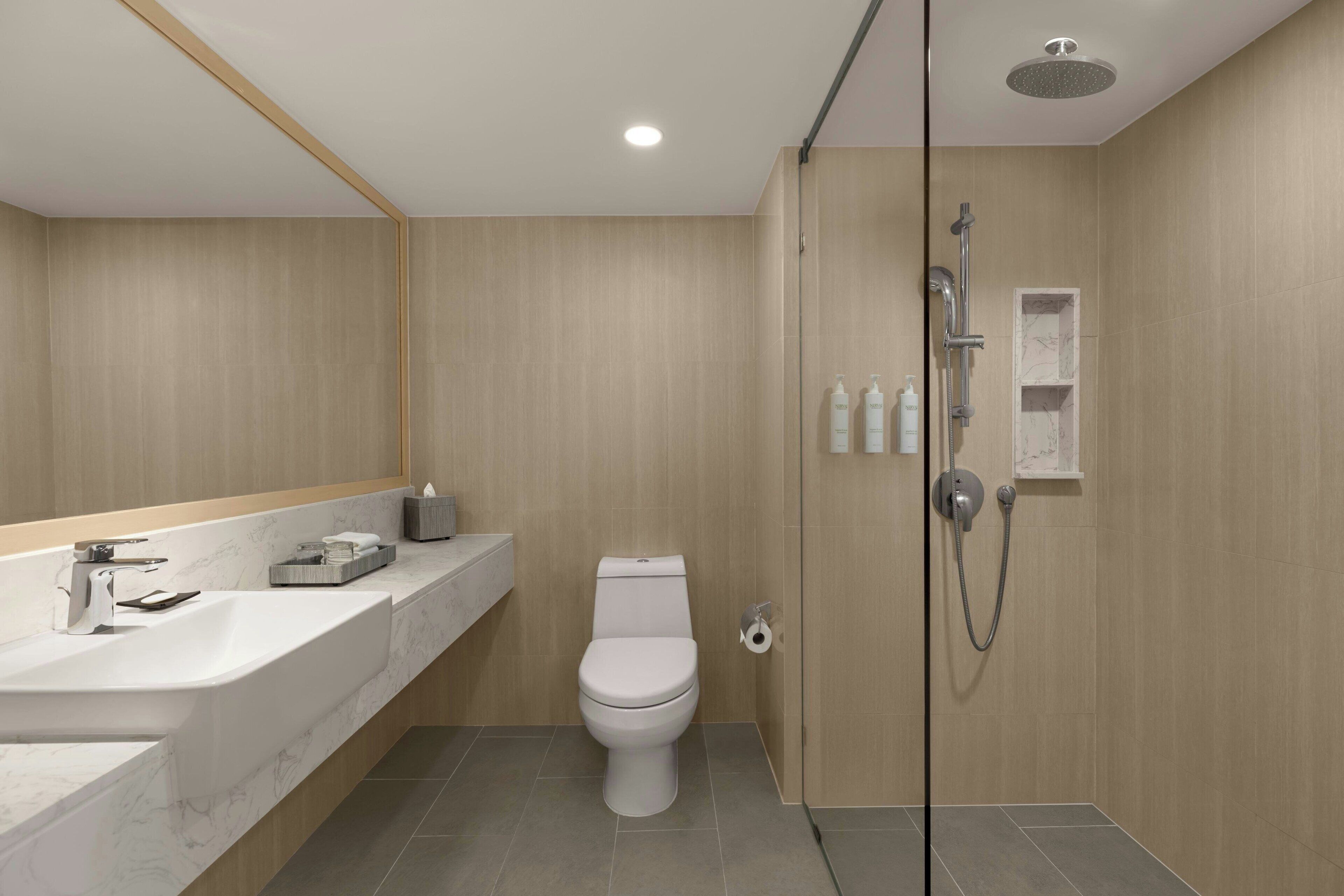 A modern bathroom with a white sink, toilet, and shower.