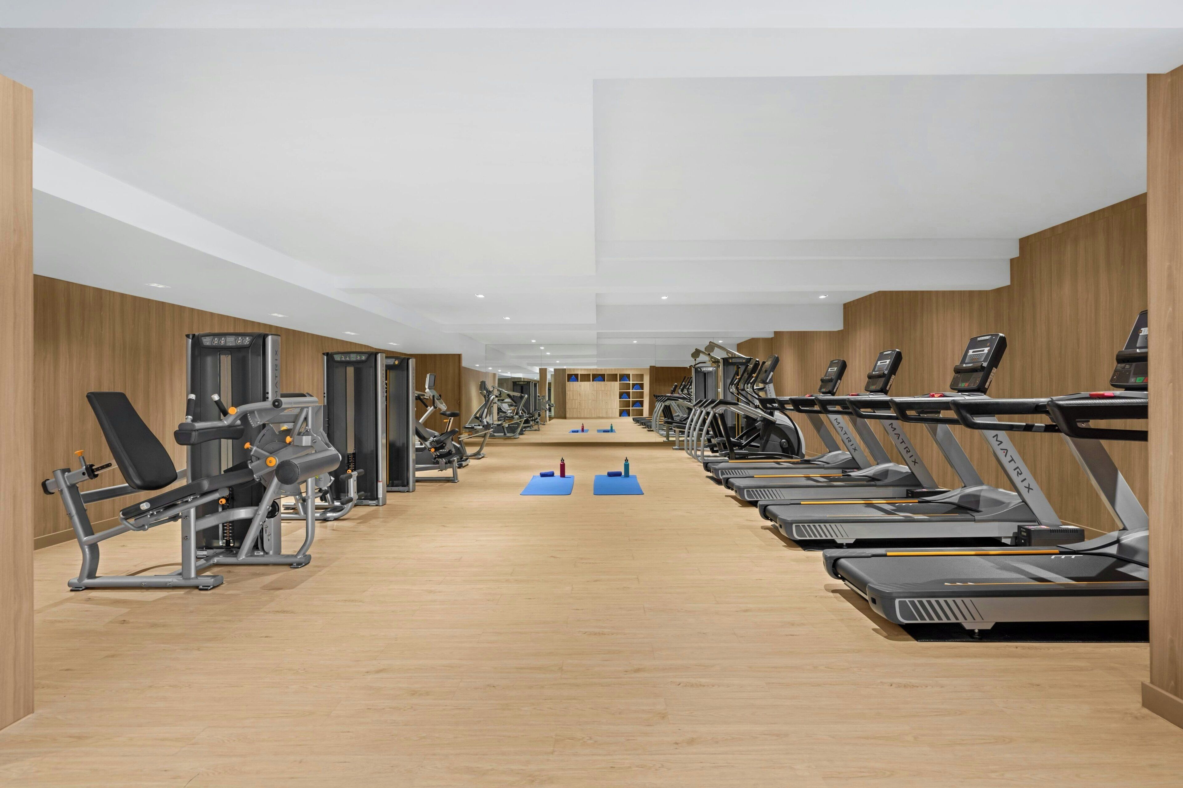 Una palestra con tapis roulant, macchinari per pesi e tappetini per esercizi.