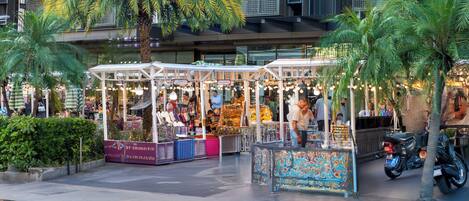 Un mercado al aire libre con puestos y palmeras.