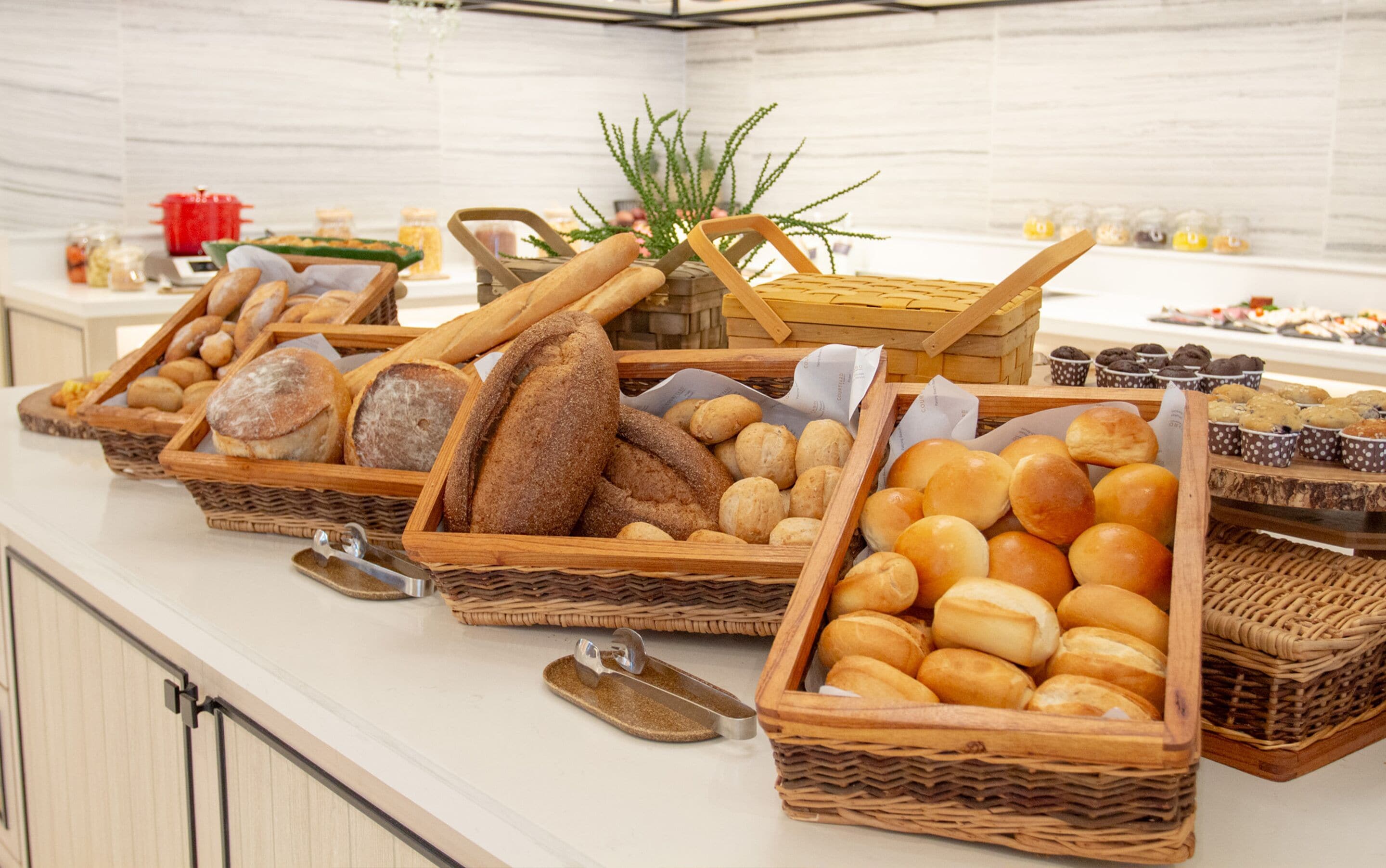 A buffet table with various breads and pastries in wicker baskets.