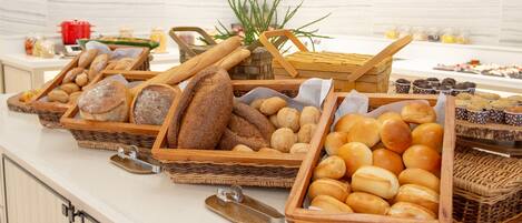 A buffet table with various breads and pastries in wicker baskets.