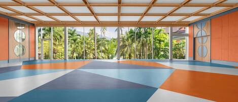 Una habitación amplia con un estampado geométrico en el suelo, ventanas grandes y vistas a palmeras.
