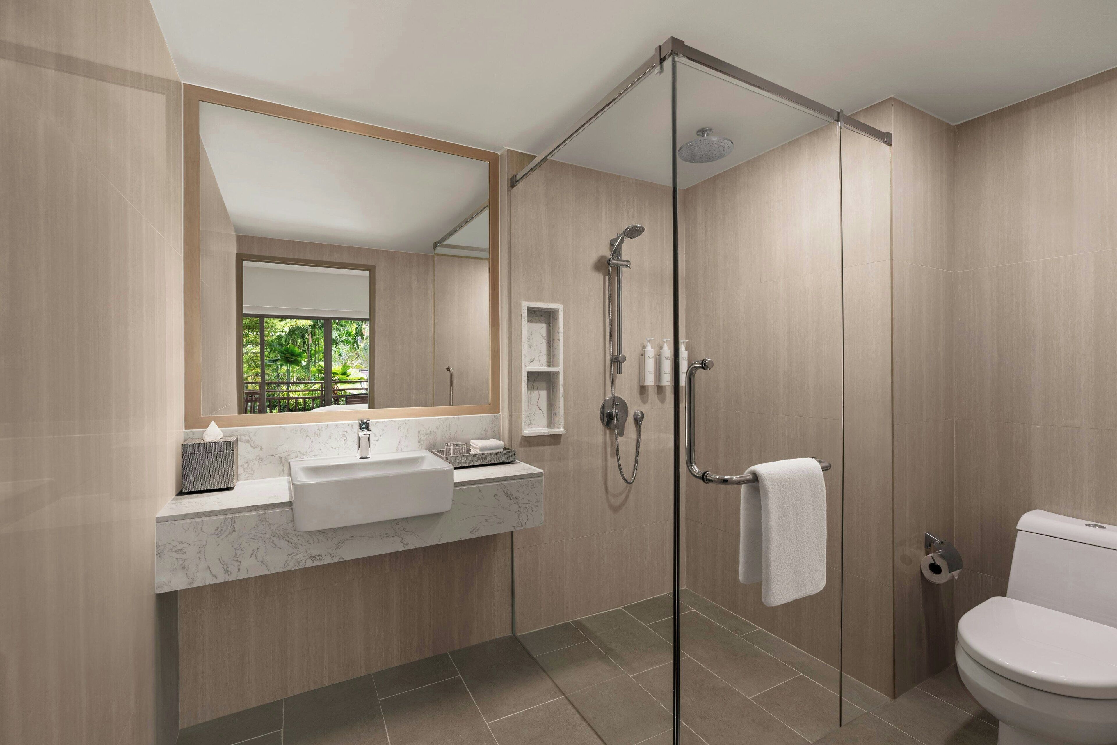 Une salle de bain moderne avec une douche à parois de verre, un lavabo en marbre et des toilettes.