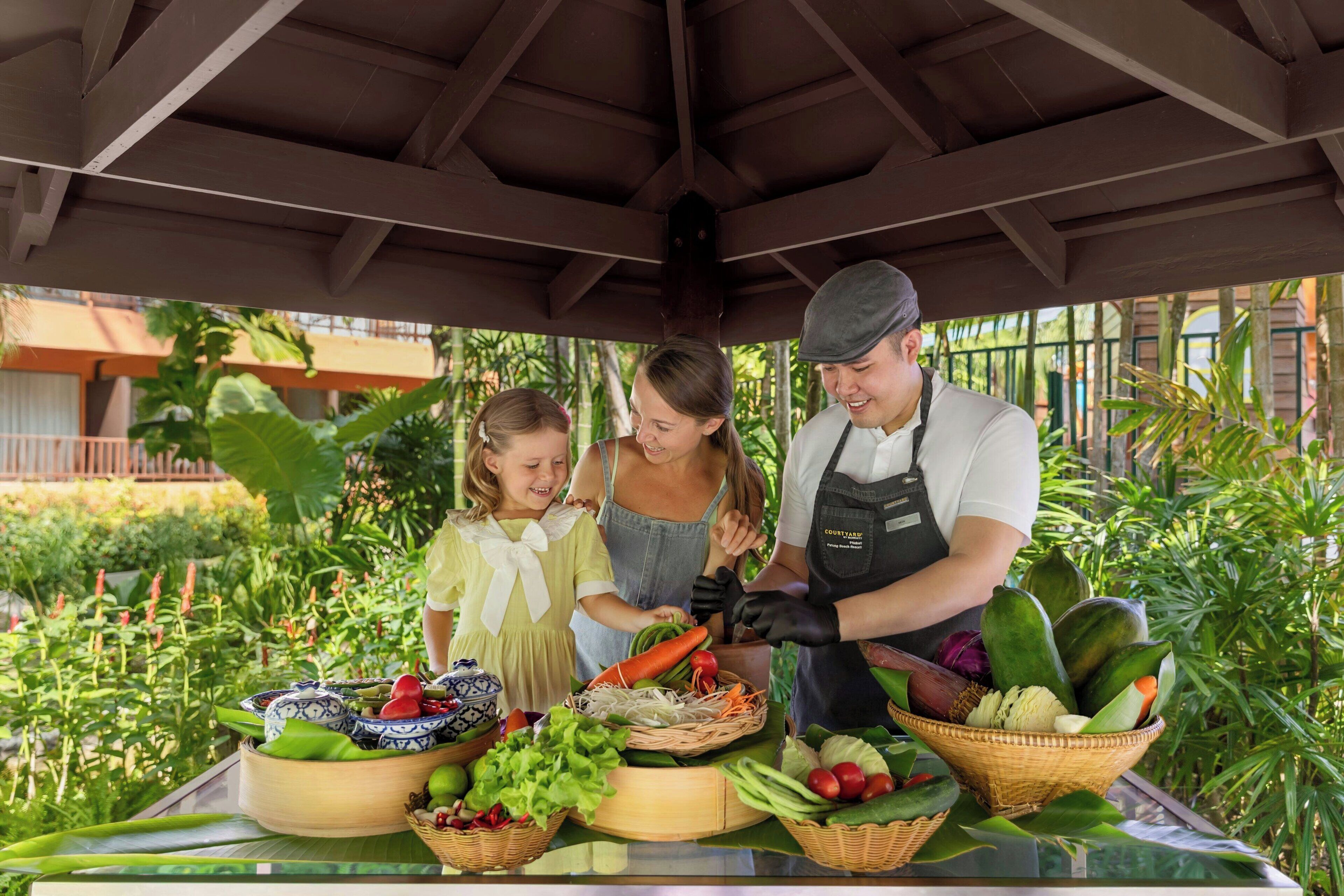 A covered outdoor area with a table displaying various fresh vegetables and fruits.