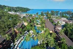 A resort with a large pool surrounded by palm trees, multiple buildings, and a view of the ocean. - Courtyard by Marriott Phuket, Patong Beach Resort (Patong)
