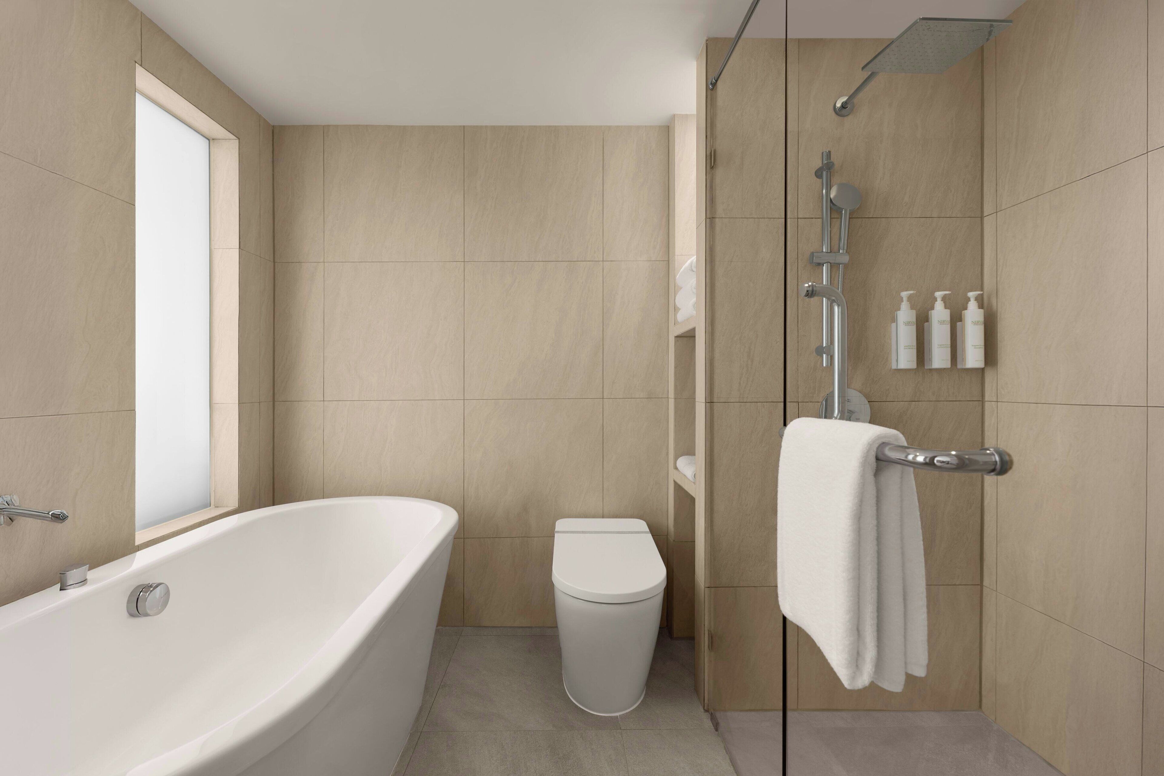 A modern bathroom with a freestanding bathtub, a toilet, and a glass-enclosed shower area.