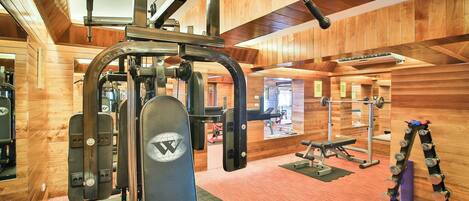Ein Fitnessstudio mit unterschiedlichen Trainingsgeräten, darunter ein Squat-Gestell, eine Hantelbank und Zubehör für das Krafttraining.