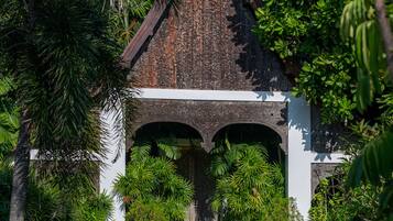 A traditional stone structure with a pointed roof, surrounded by lush greenery and a well-maintained garden.