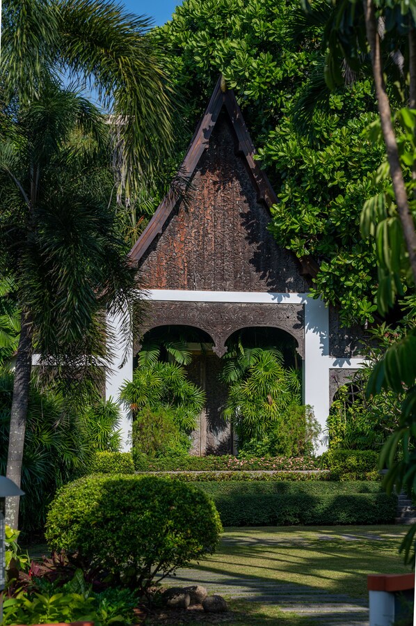 A traditional stone structure with a pointed roof, surrounded by lush greenery and a well-maintained garden.