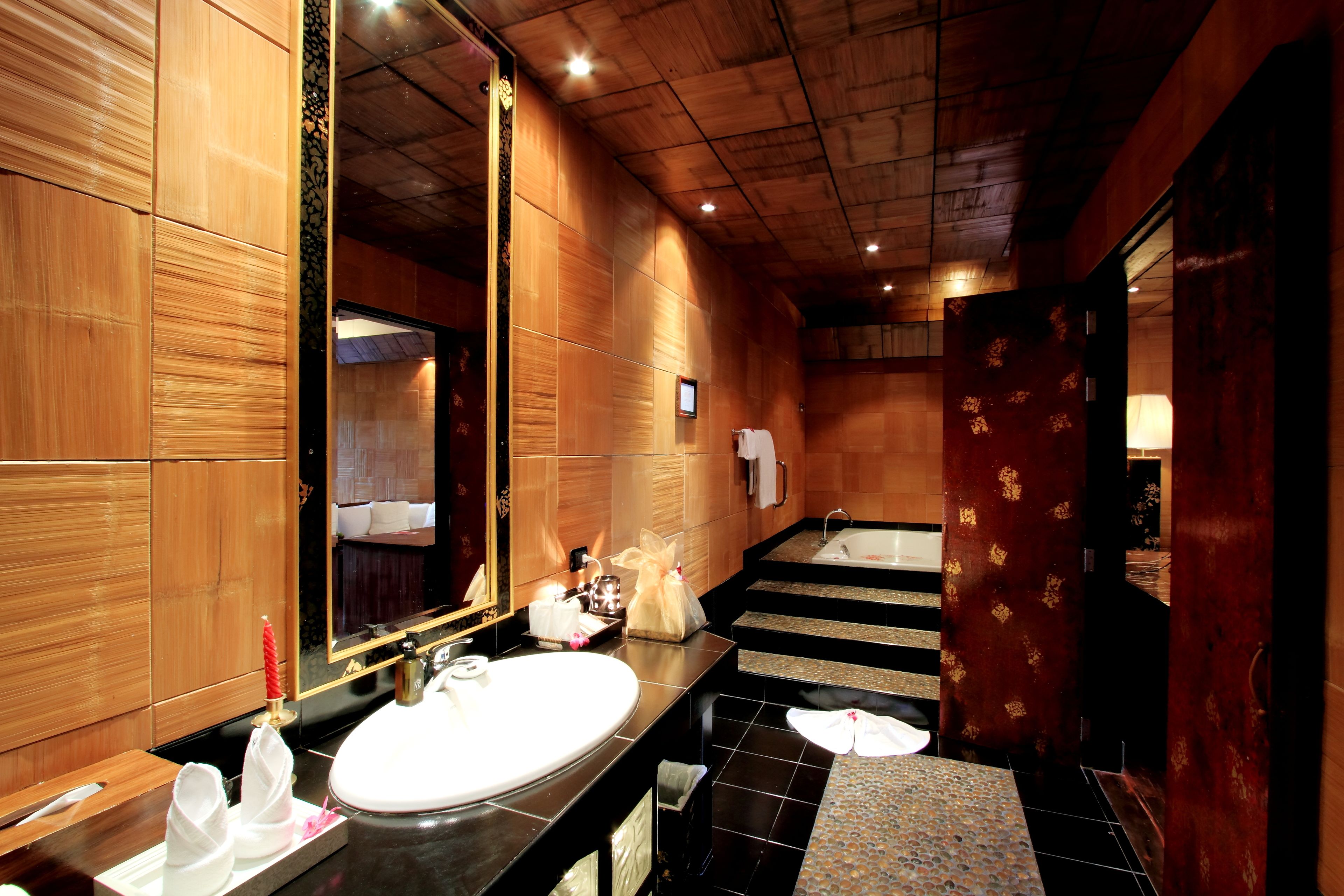 A modern bathroom with a large mirror, wooden paneling, a sink, and a bathtub.