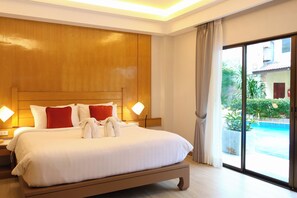 A hotel room with a large bed, two bedside lamps, a view of a swimming pool, and a sliding glass door. - Baan Boa Resort  (Patong)