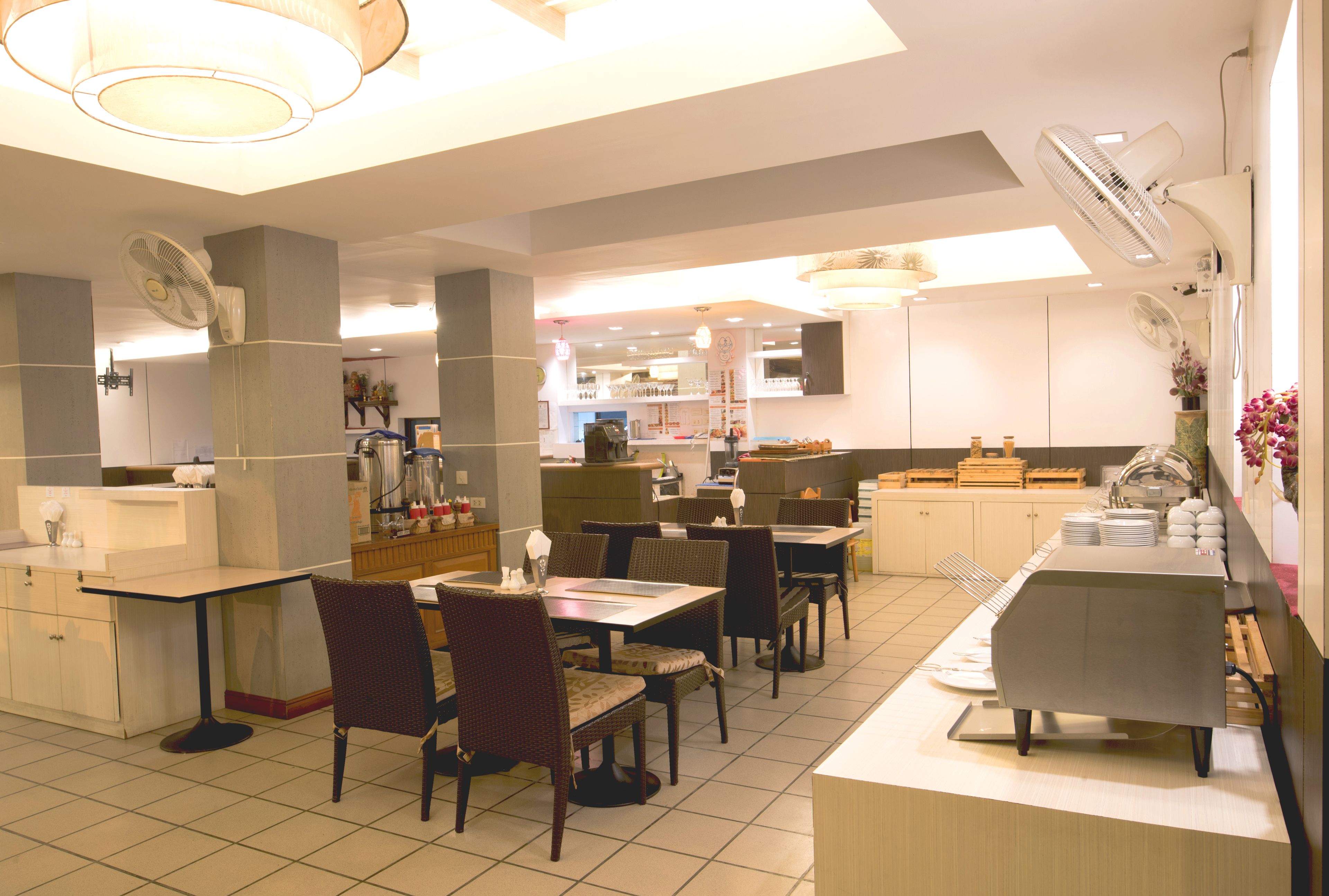 A restaurant with multiple dining tables and chairs, a buffet counter, and ceiling fans.