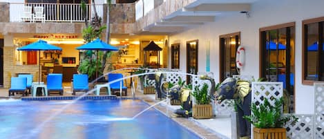 A pool area with lounge chairs, umbrellas, and decorative elephant statues.