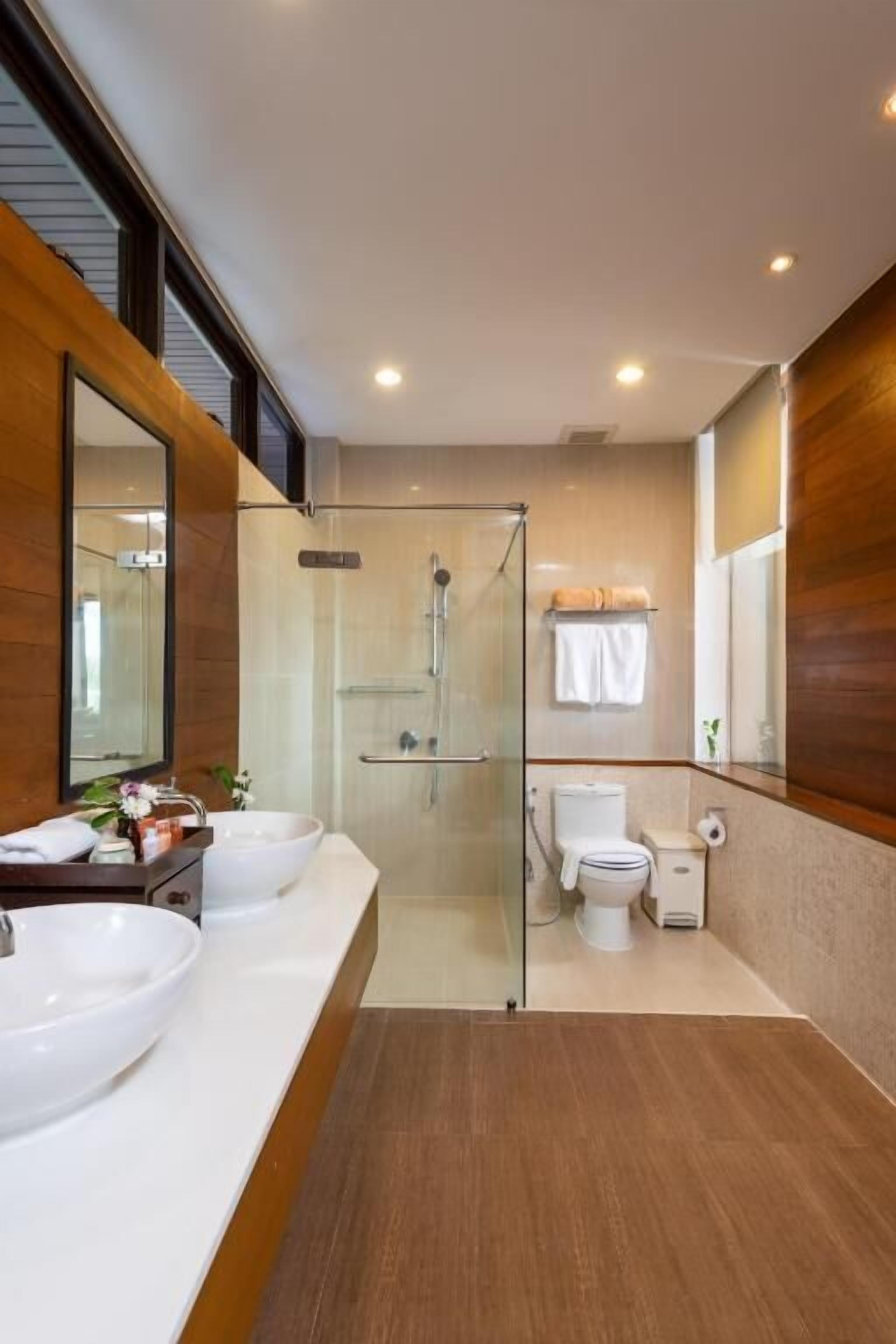 A modern bathroom with a glass-enclosed shower, a large mirror, and a white sink.