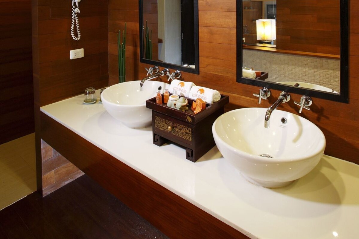 Un baño moderno con dos lavamanos, un espejo grande y un mueble de tocador de madera.
