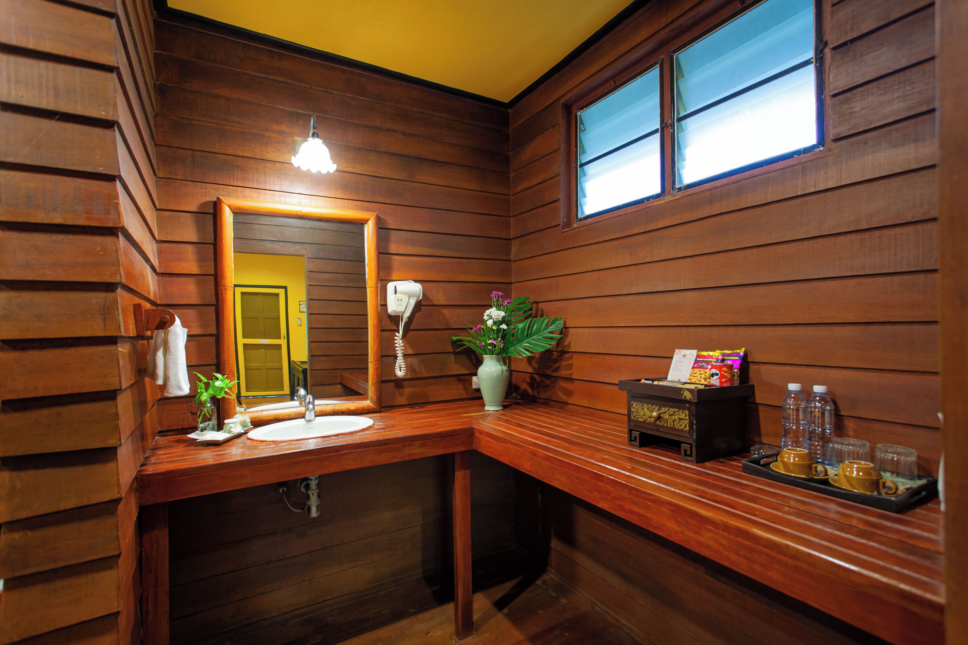 Un baño de estilo cabaña de madera con lavamanos, espejo y una planta pequeña.