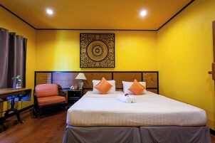 A hotel room with a large bed, two pillows, a nightstand, a chair, and a decorative wall piece.