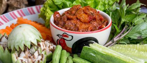Une assiette contenant divers légumes et un bol de sauce pour tremper.