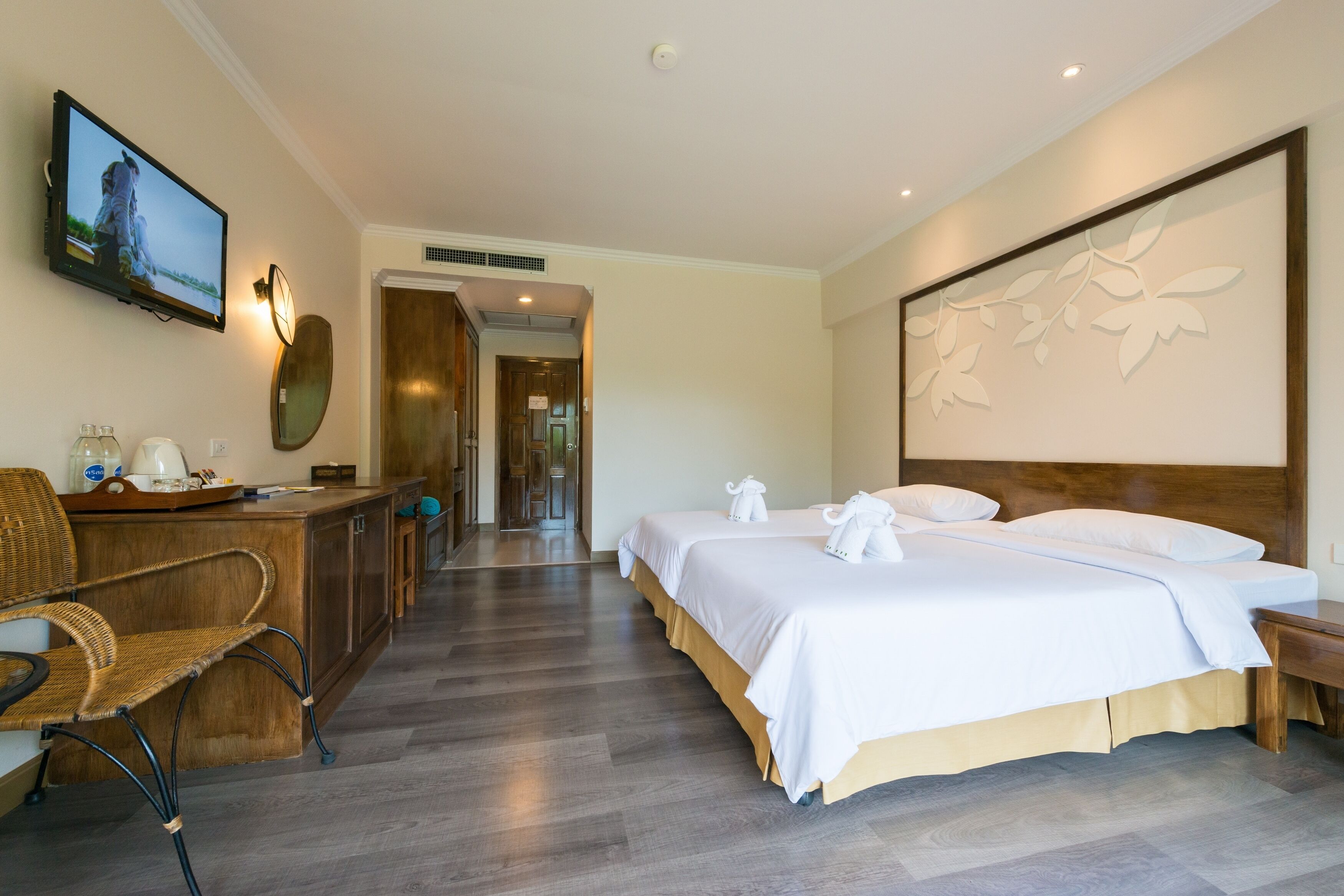A hotel room with a large bed, a desk with a chair, a television, and a decorative wall piece.