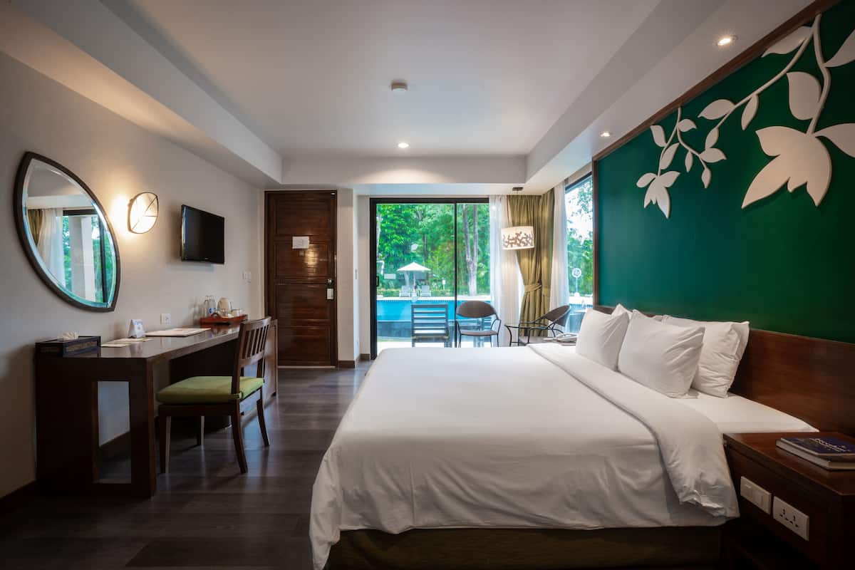 Habitación de hotel con una cama grande, un escritorio con silla, televisor montado en la pared y vistas al exterior.