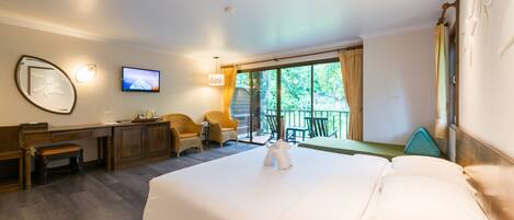 A hotel room with a large bed, a desk, a chair, and a TV on the wall.