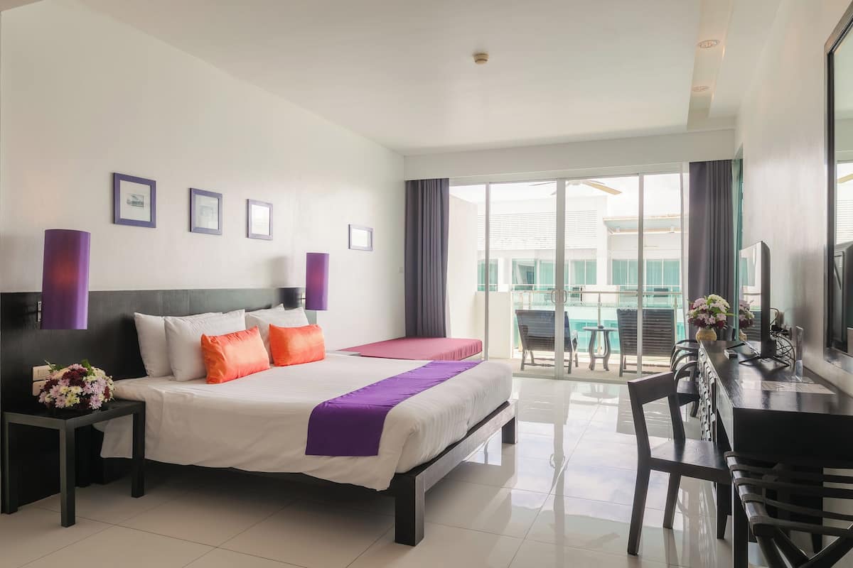Een moderne hotelkamer met een groot bed, een bureau en een balkon met uitzicht.