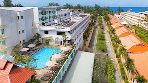 Un hotel con piscina, varios pisos y vista al océano.