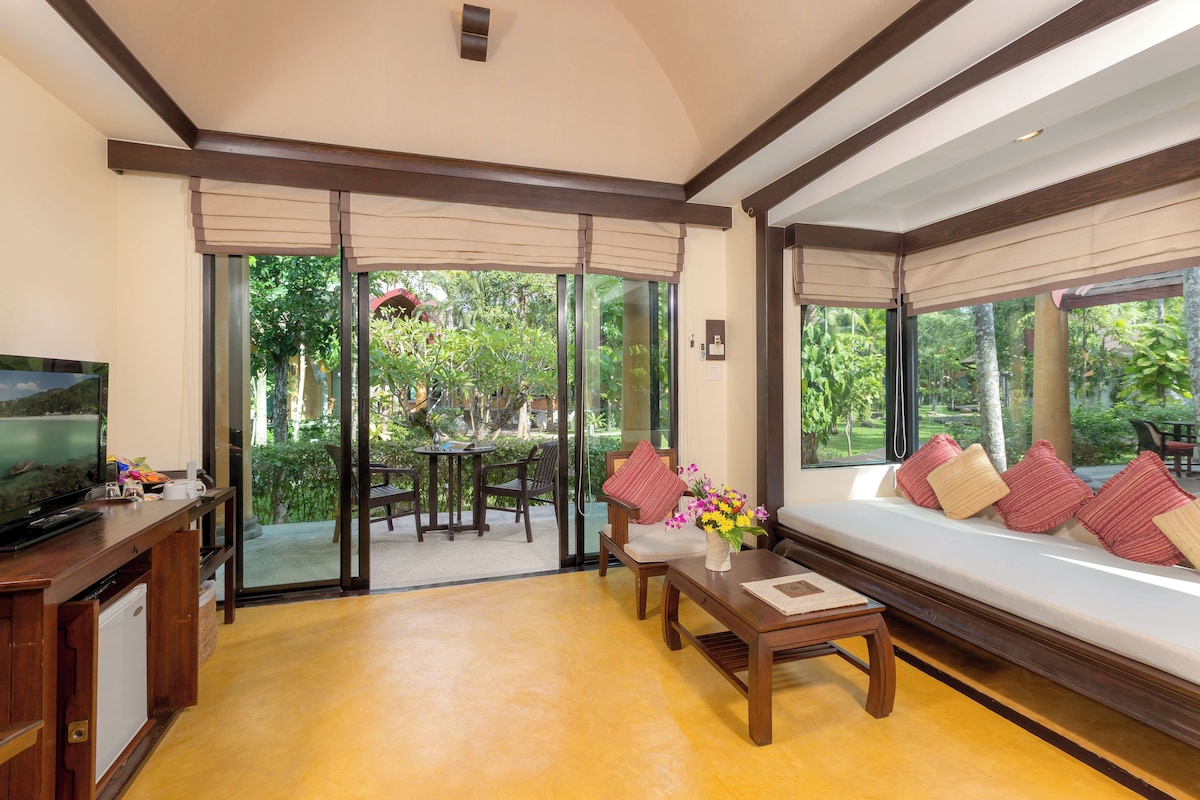 Una habitación con sofá, televisión, mesita de centro y vistas al exterior.