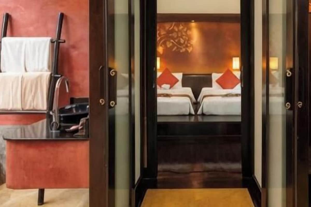 A hotel room with a bed, a robe hanging on the wall, and a towel rack.