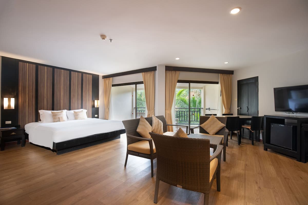 A modern hotel room with a large bed, a dining area, and a TV.