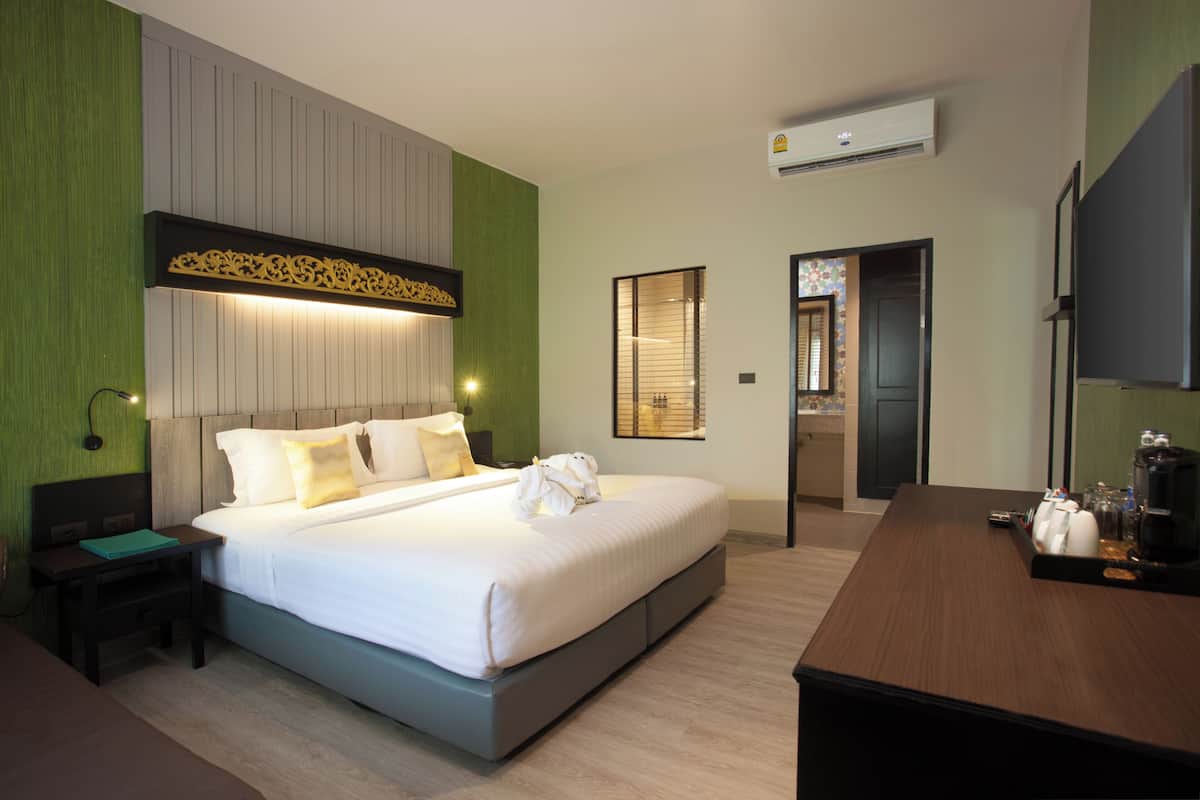 A modern hotel room with a large bed, bedside tables, a desk with a chair, and a TV.