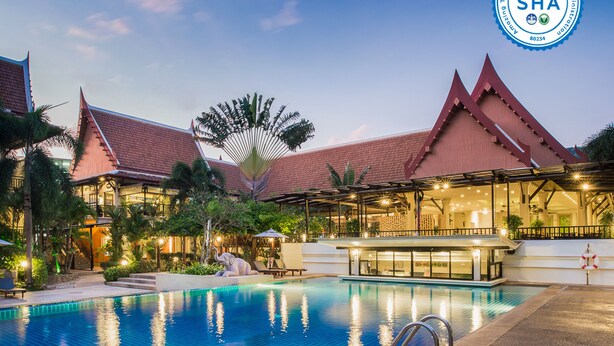 Un resort con piscina, arquitectura tradicional y un espacio cubierto con asientos.