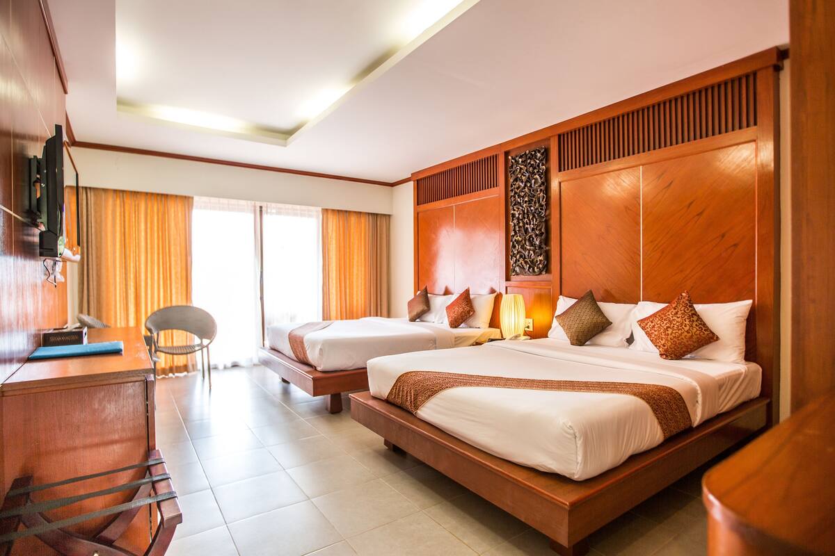 Une chambre d’hôtel avec deux lits, un bureau, une chaise et un téléviseur.