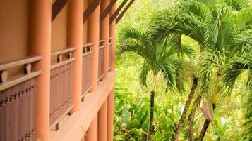 Un edificio con balcón y columnas, rodeado de exuberante vegetación y palmeras.