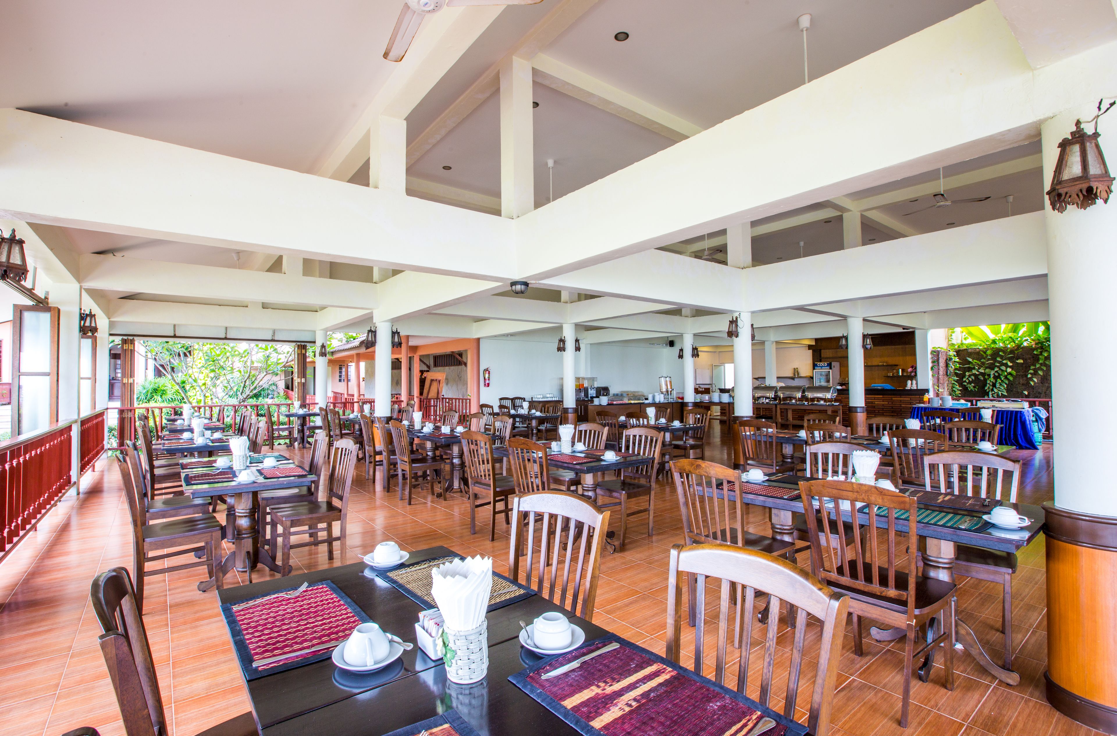 A spacious dining area with multiple tables and chairs, high ceilings, and large windows allowing natural light.