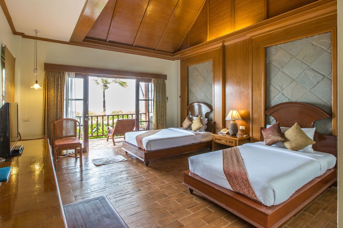 Une chambre d’hôtel avec deux lits, un balcon, un plancher en bois et une télévision.