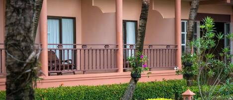 A hotel with a two-story structure, balconies with railings, and a well-maintained garden with various plants and a small decorative lamp.