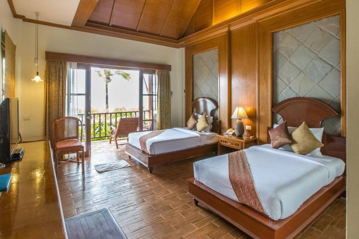 Une chambre d’hôtel avec deux lits, un balcon, un plancher en bois et une télévision.