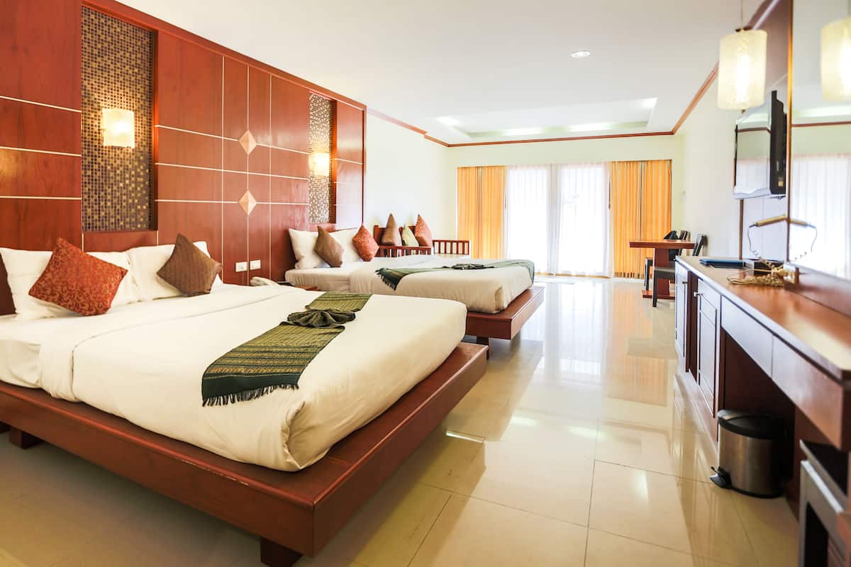 Une chambre d’hôtel avec deux lits, une tête de lit en bois, une télévision et un minibar.