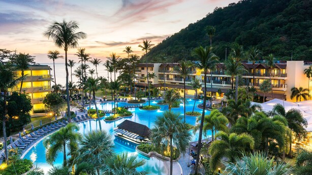 A resort with multiple swimming pools, palm trees, and a mountainous backdrop. - Phuket Marriott Resort & Spa, Merlin Beach (Patong)