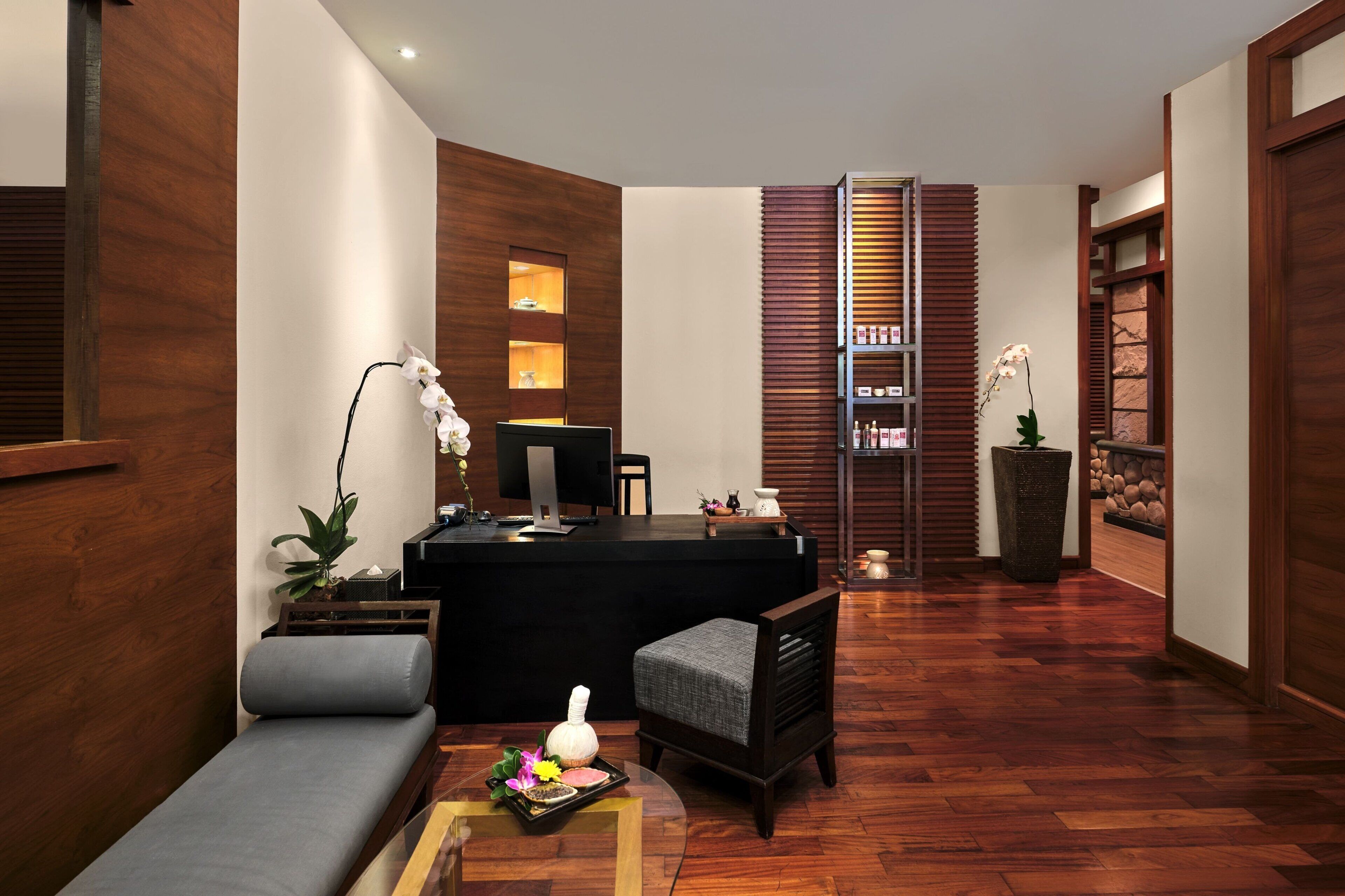 A modern reception area with a wooden reception desk, a grey sofa, and a small table with a tray of items.