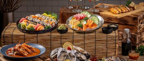 A variety of seafood dishes, including sushi, sashimi, and grilled fish, arranged on wooden tables.