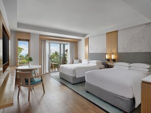 A hotel room with two beds, a desk, a chair, a TV, and a balcony with a view.