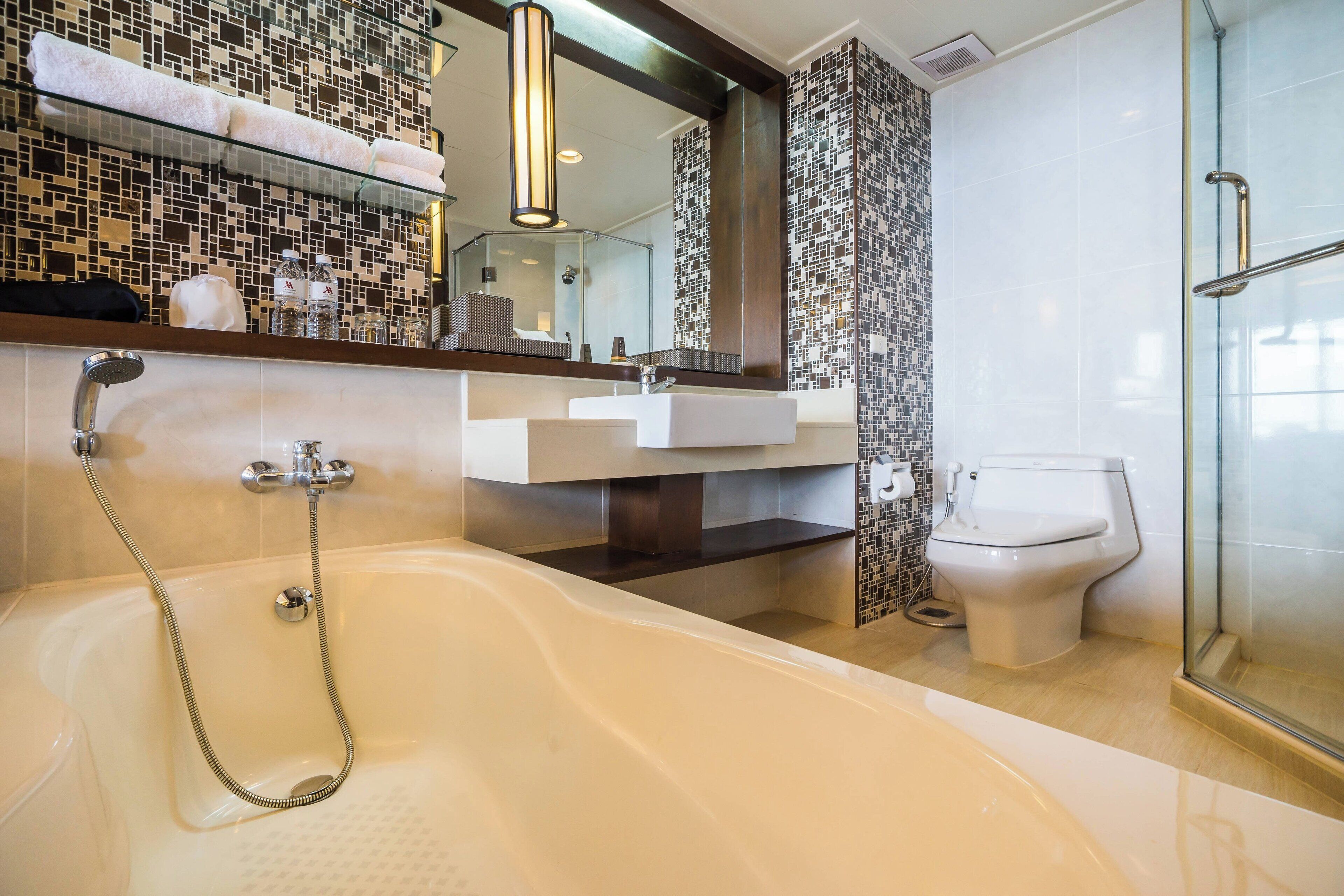 A modern bathroom with a bathtub, a glass shower enclosure, a white sink, and a toilet.