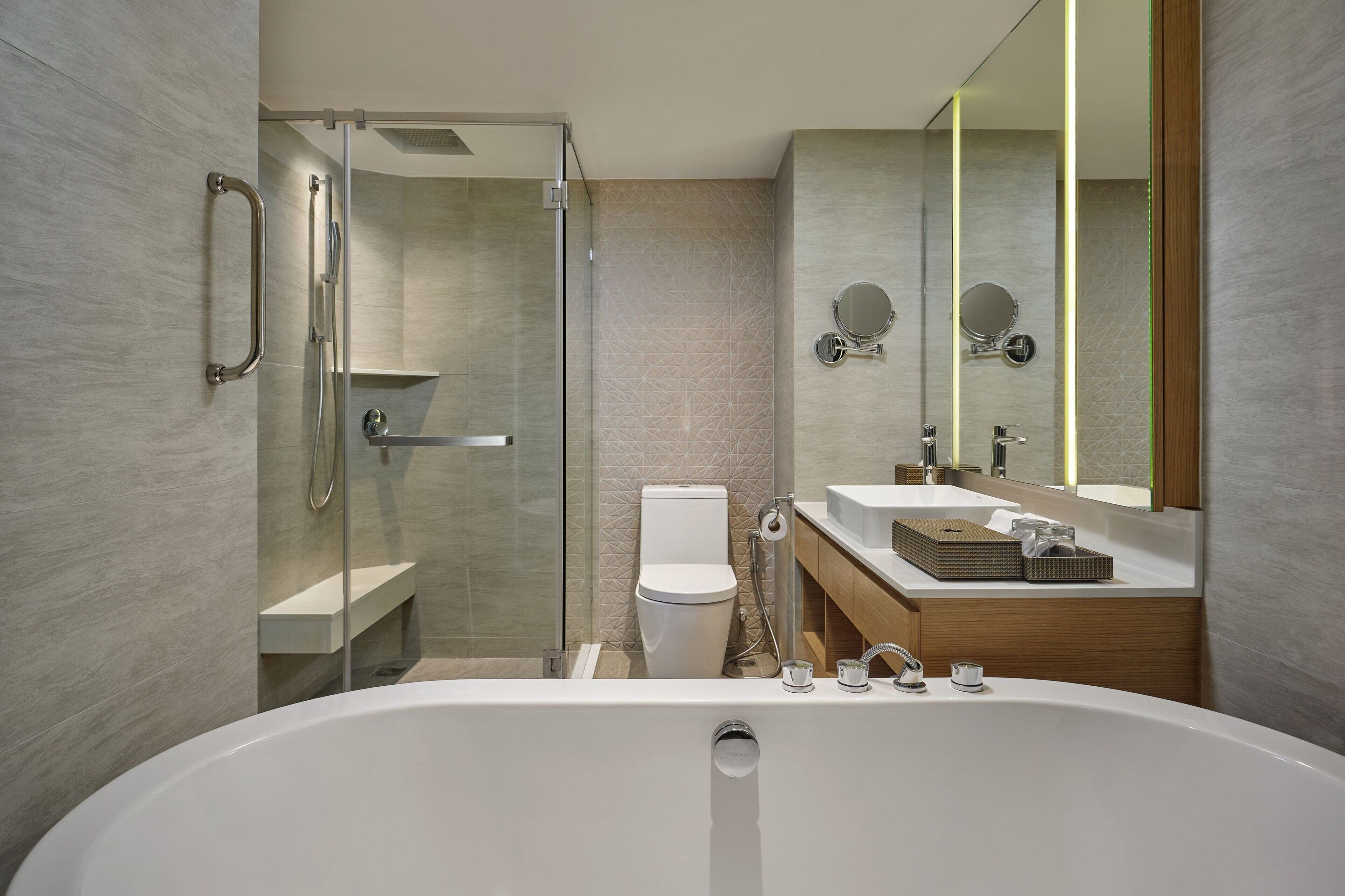 A modern bathroom with a glass-enclosed shower, a toilet, a bathtub, and a vanity with a mirror.