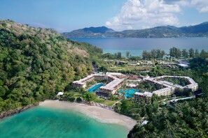 A resort with multiple swimming pools, a beach, and lush greenery.