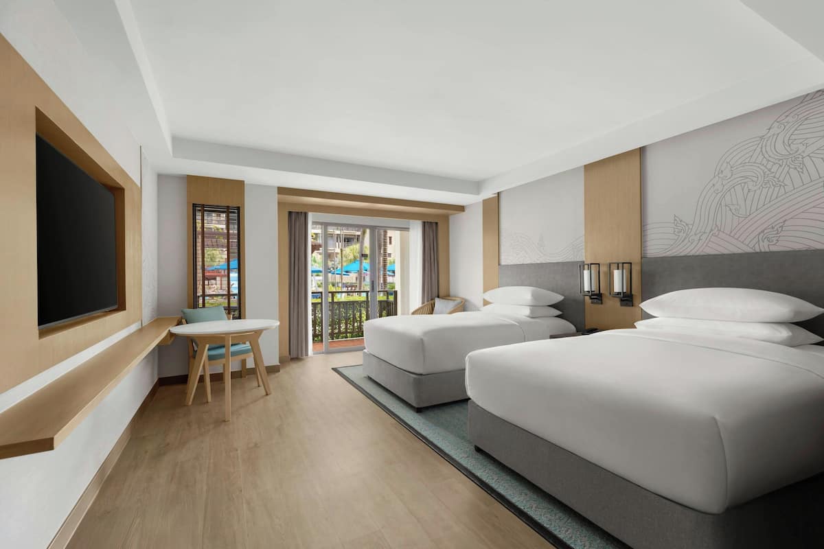 A hotel room with a large bed, a desk, and a view of the outside.