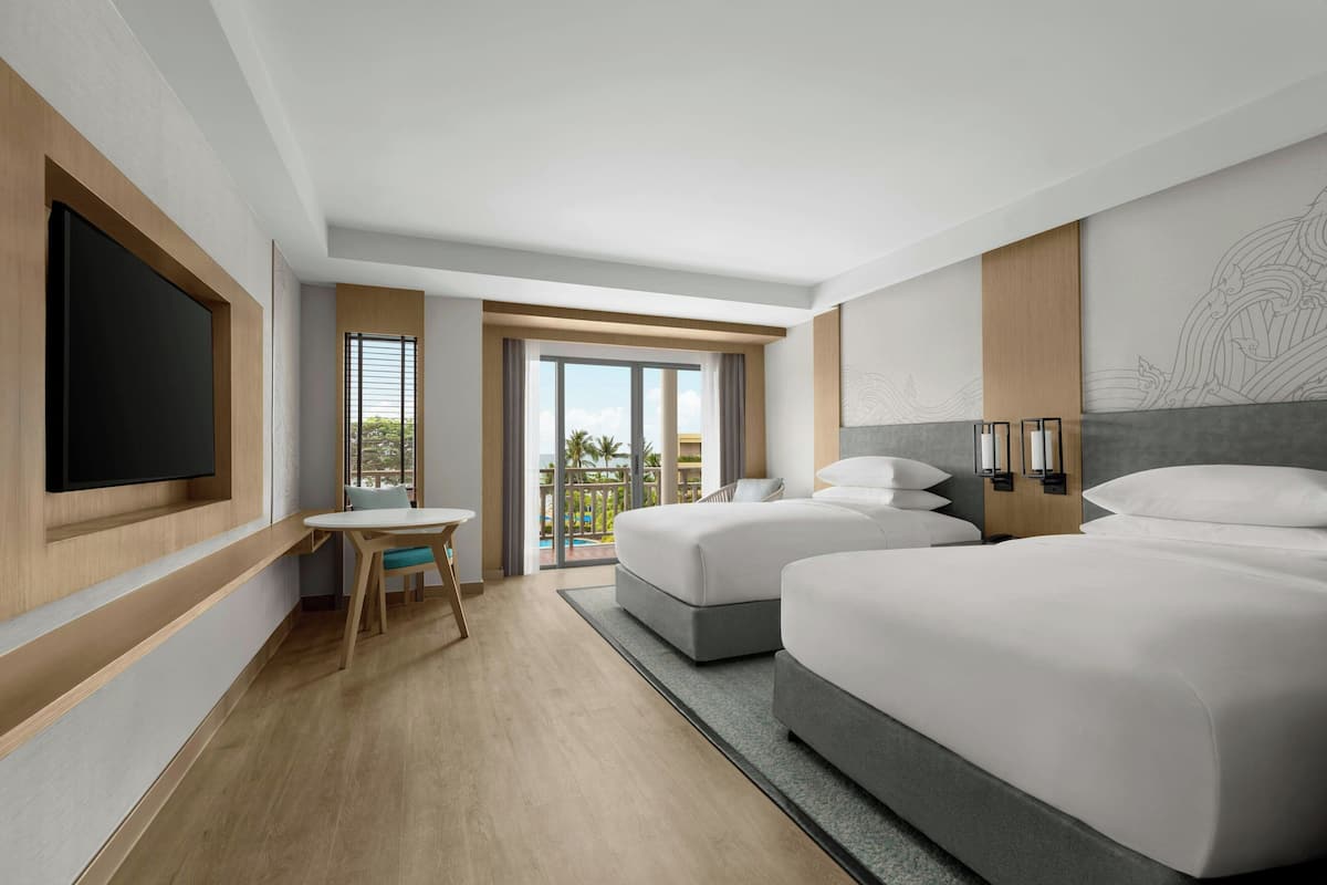 A modern hotel room with two beds, a flat-screen TV, a small table, and a balcony with a view.
